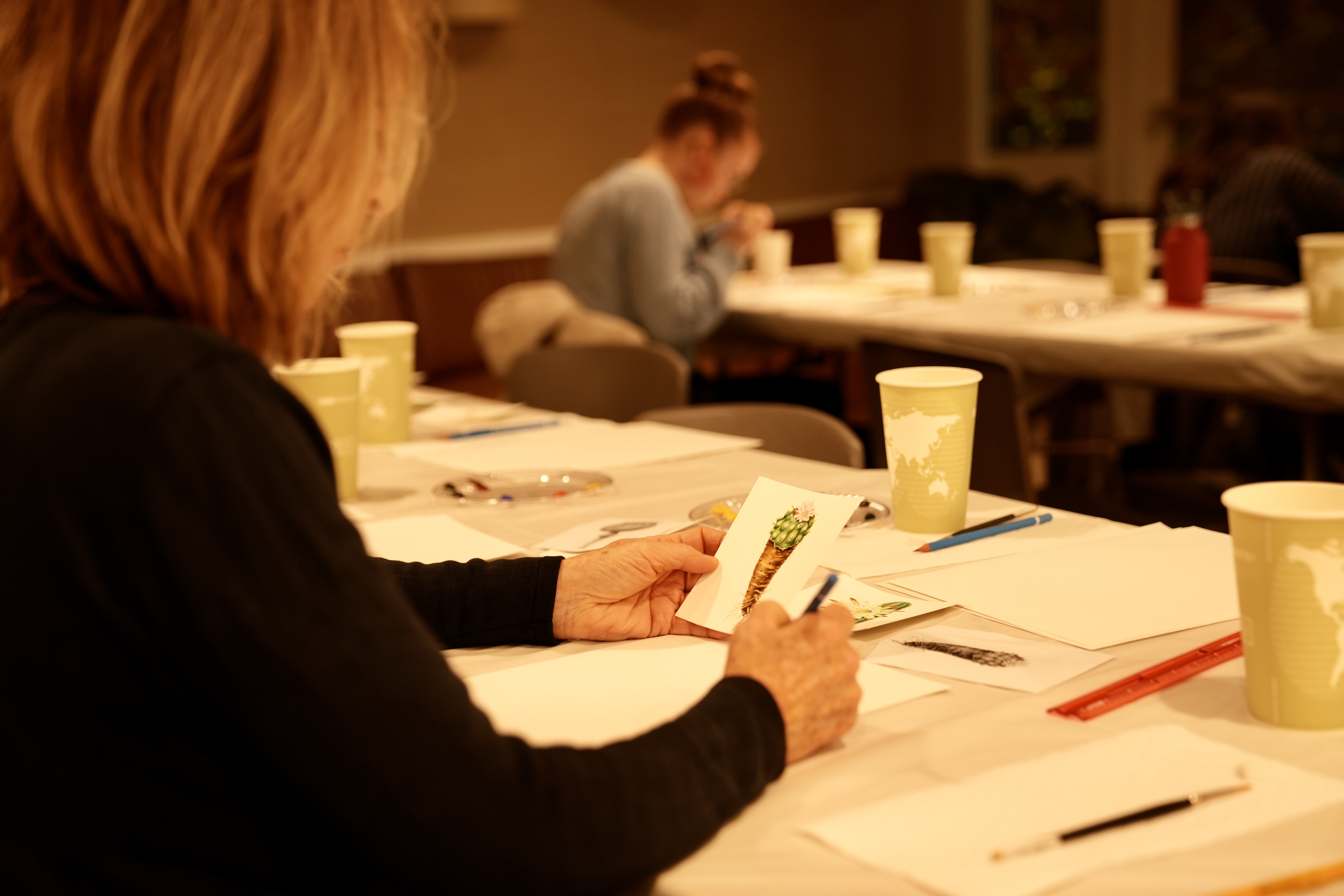 Woman sitting at the painting table looking at a plant image