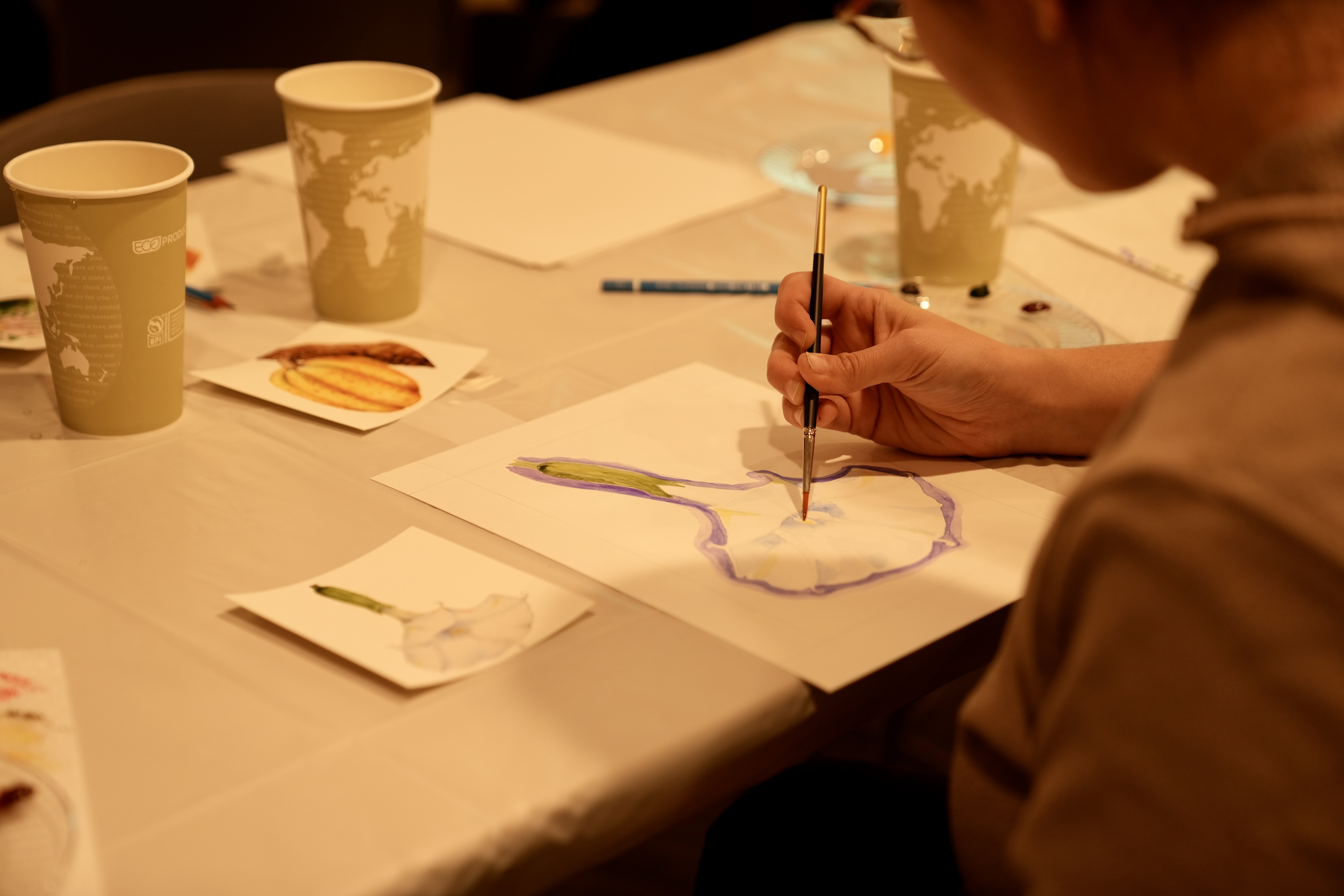 Painter at the table using a brush to paint a flower