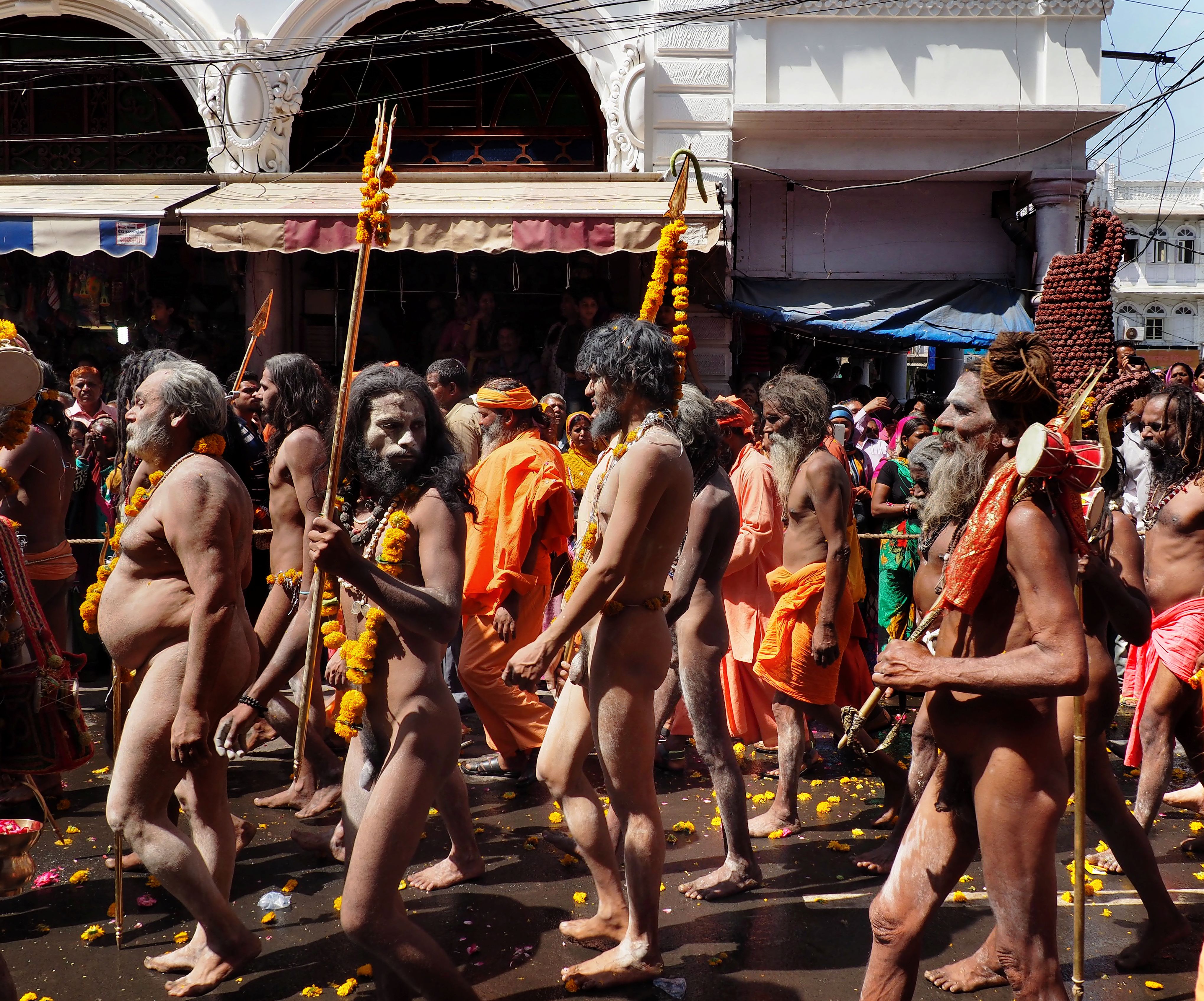 A group of sadhus walking on the street, some carrying sticks