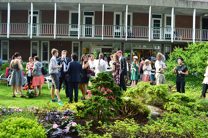 Picture of grassy courtyard with many people standing about enjoying themselves.