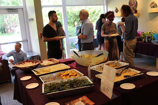 Photo of the CSWR Common Room with tables of food and people standing about talking and eating.