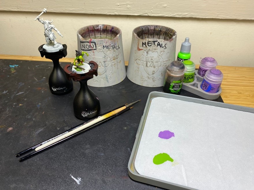 Paints, brushes and Warhammer Figurines on a table