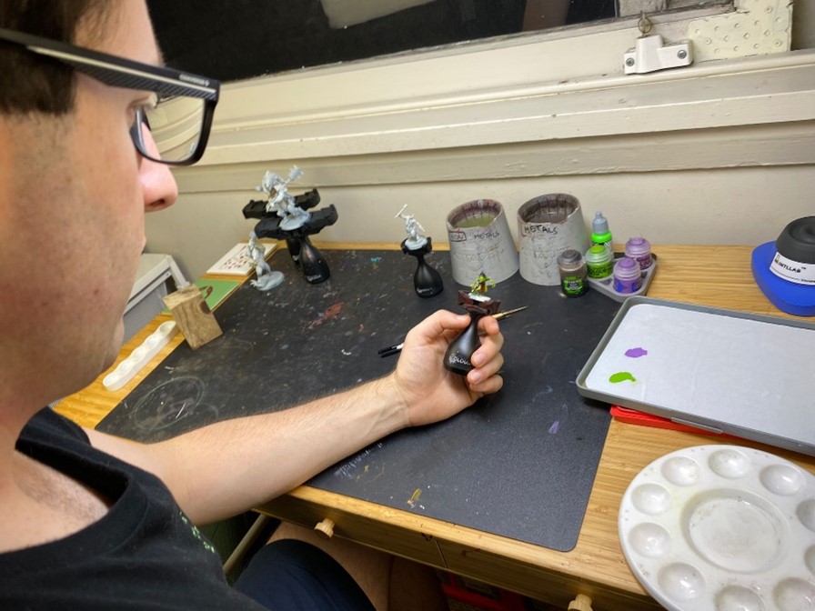 Gamer/Artist looking down at his Warhammer figurine.