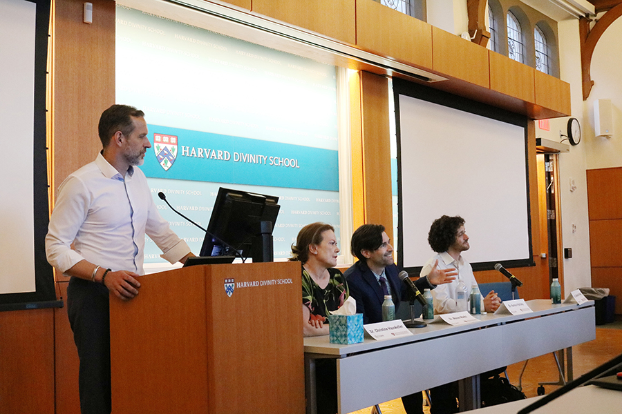 CSWR Director Charles Stang stands at a podium with several panelists seated behind a table in the Sperry Room at Swartz Hall at Harvard Divinity School.