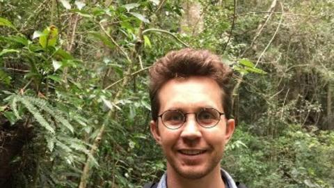Photo of Alex Gearin smiling in the jungle