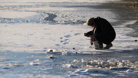 Person kneeling on the frozen pond