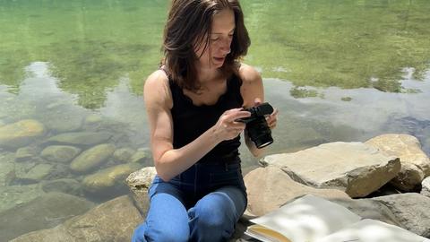 Sarah Schorr siting at the edge of Walden Pond photographing art work