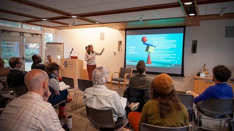 Instructor gesturing towards an image on the screen while participants look on