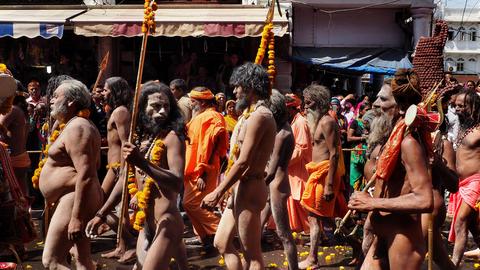 A group of sadhus walking on the street, some carrying sticks