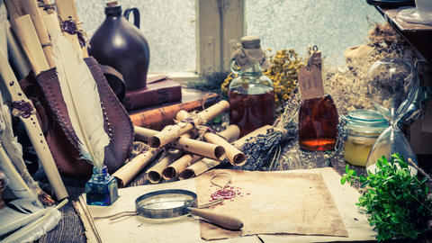 Lab desk with magnifying glass, scrolls, plant specimens, and tinctures