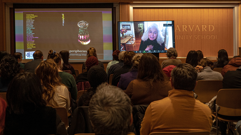 Photo of crowd watching poet Jorie Graham read via Zoom broadcast
