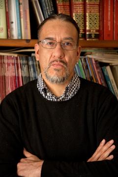 Headshot of scholar Osiris Gonzalez Romero in front of a bookshelf