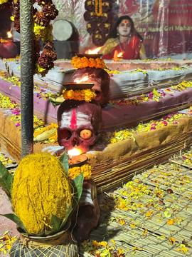 Religious altar with icons and skulls. Woman with face painted sitting behind altar.