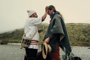 Man in white shirt touching another man's forehead, river in the background