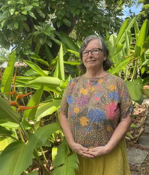 Donna Torres standing, hands folded in front of a cluster of plants
