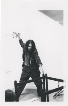 Artist standing in motion to swing an object onto a small fence