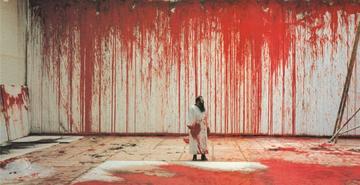 Artist Nitsch during his painting performance, against white large canvas and floor painted in red paint