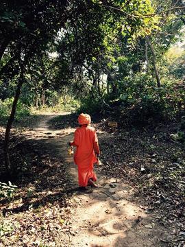 Person in orange robes and head scarf walking along a pathway