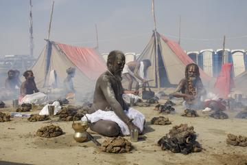 Men seated around small rock fires, tents in the background