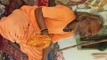 Man seated with eyes closed and holding scarf
