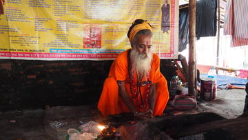 Man squating in front of alter, banner in background