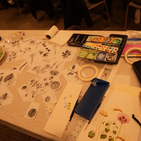 table of painting supplies and cutout paper of plant paintings
