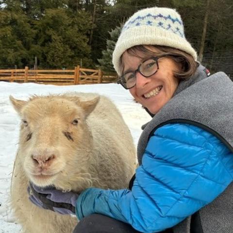 Rebecca Gould smiling sitting next to a sheep