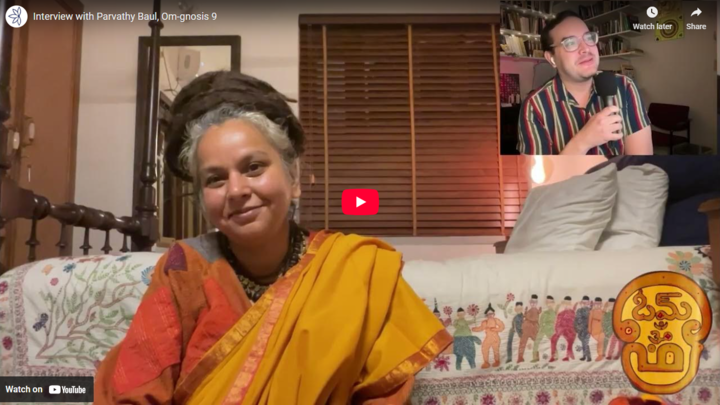 Parvathy Baul seated smiling into the camera. Keith Cantu in the upper right corner of the image.