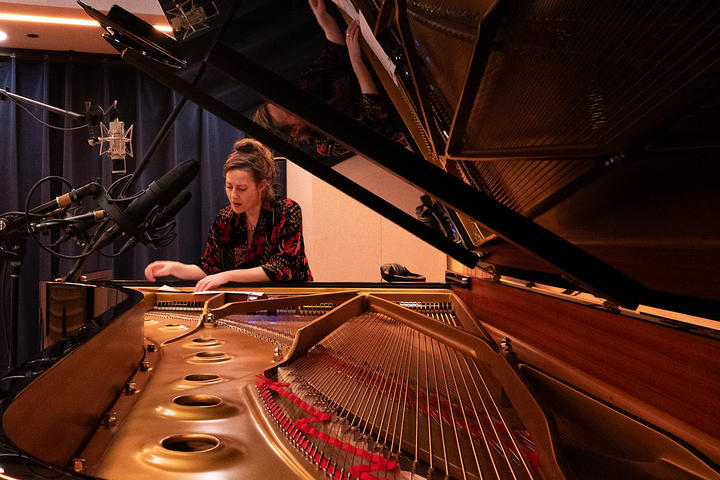 Jane Sheldon at the piano, vantage point of the image looking over top of the piano strings
