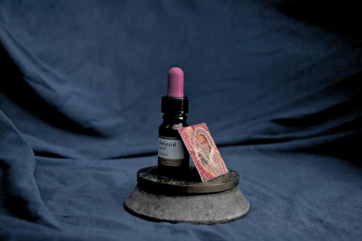 Vial of LSD sitting on a small round platform on a surface draped by blue cloth of some kind