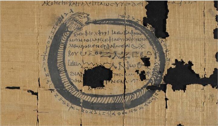 Ancient papyrus with image of snake eating tail with text in the middle of the image