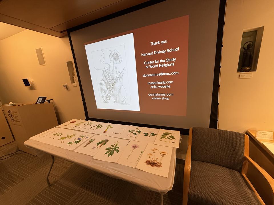 Table with art prints arranged, backdrop of projection screen with Thank You HDS and Donna Torres contact information.