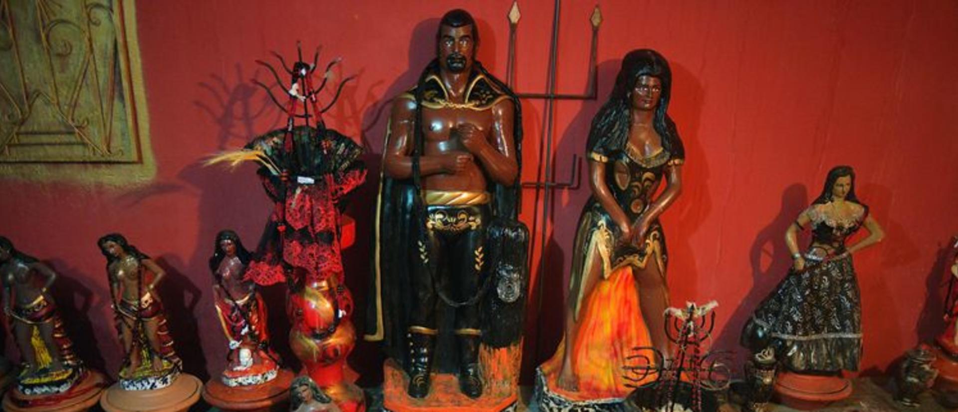 A collection of Exus (male) and Pombagiras (female) in a temple space 
