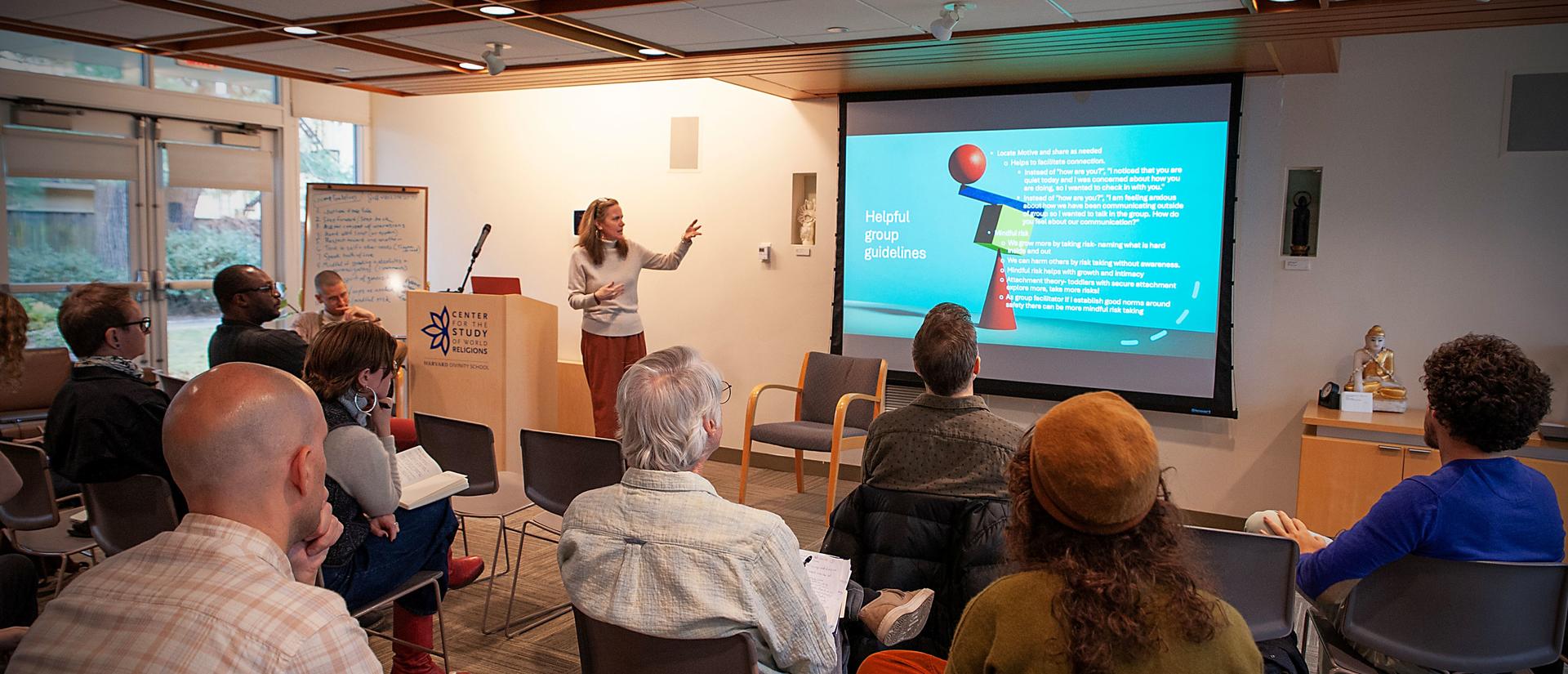 Instructor gesturing towards an image on the screen while participants look on