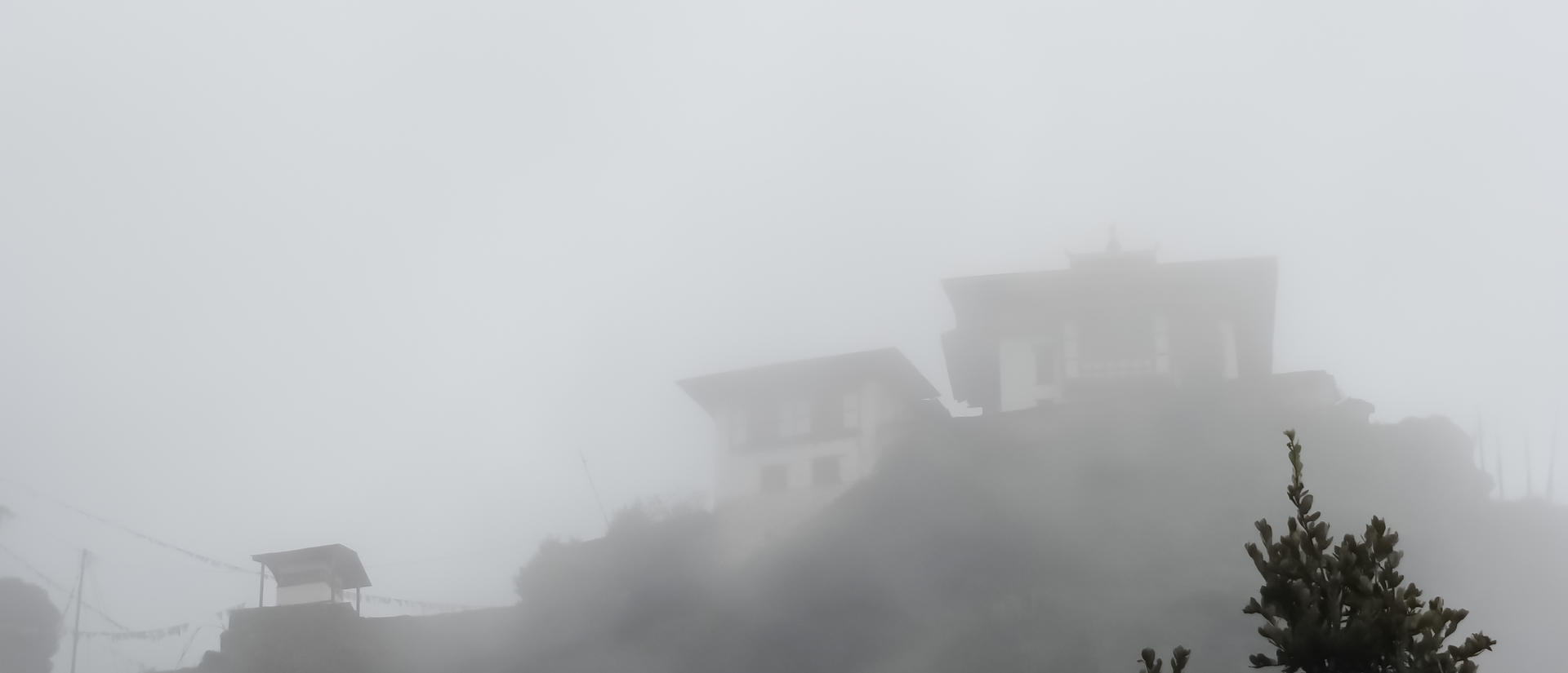 Two asian huts atop a mountain in the mist