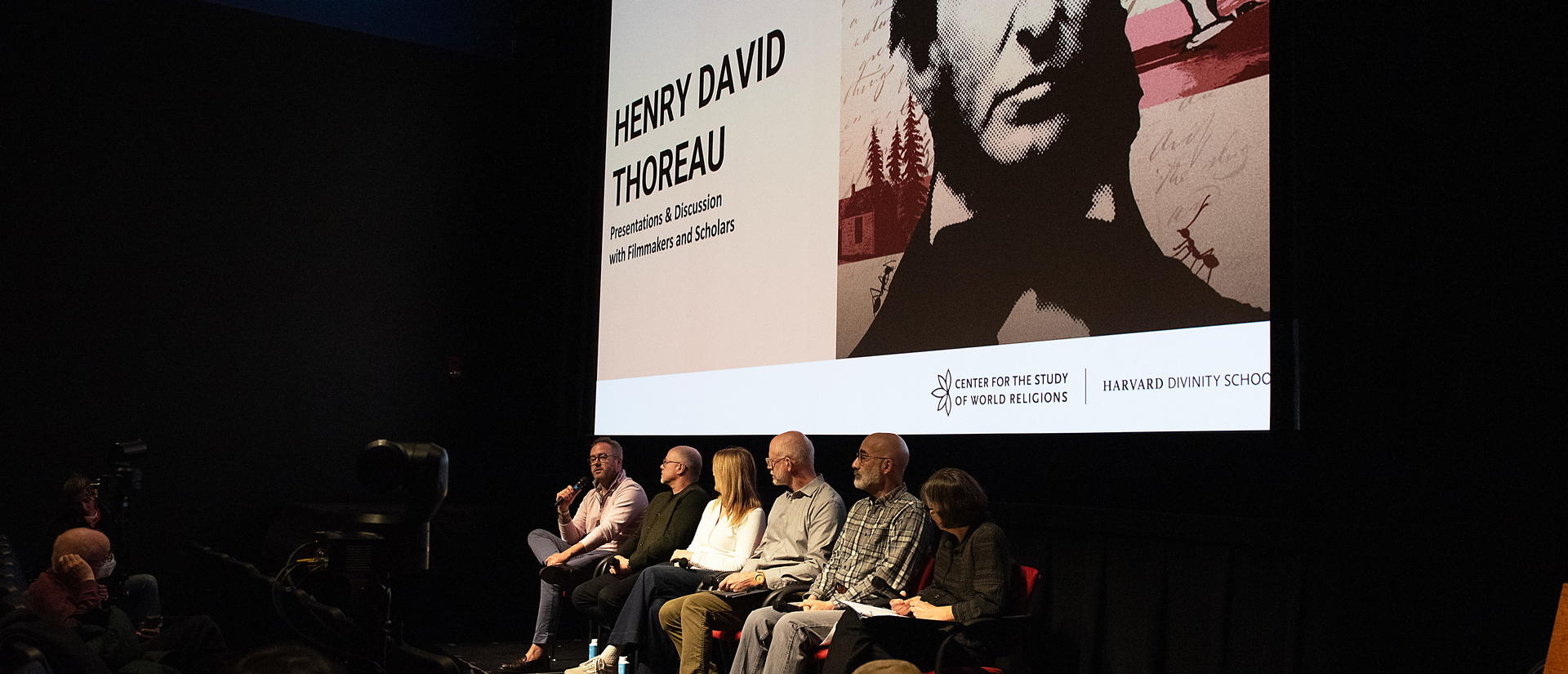 Image of speakers discussing Thoreau's works in front of a screen with Thoreau's image