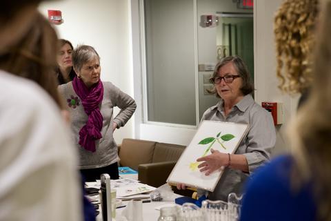 artist donna torres stands and show botanical paint to group