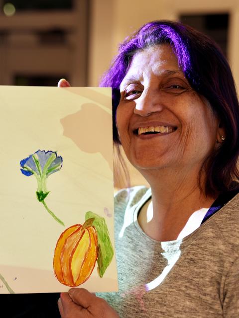 Workshop participant holding up painting smiling.