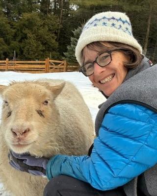 Rebecca Gould smiling sitting next to a sheep