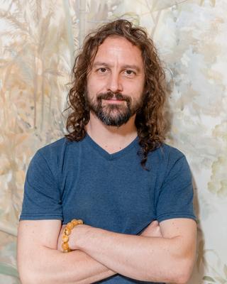 Simon Cox, arms crossed, smiling into the camera