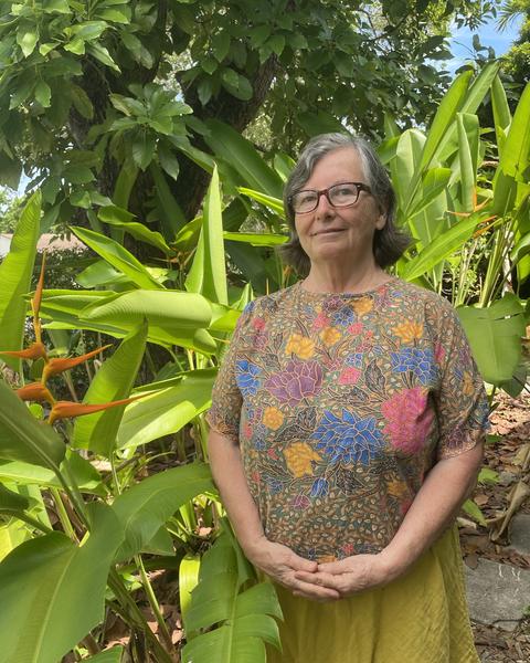 Donna Torres standing, hands folded in front of a cluster of plants