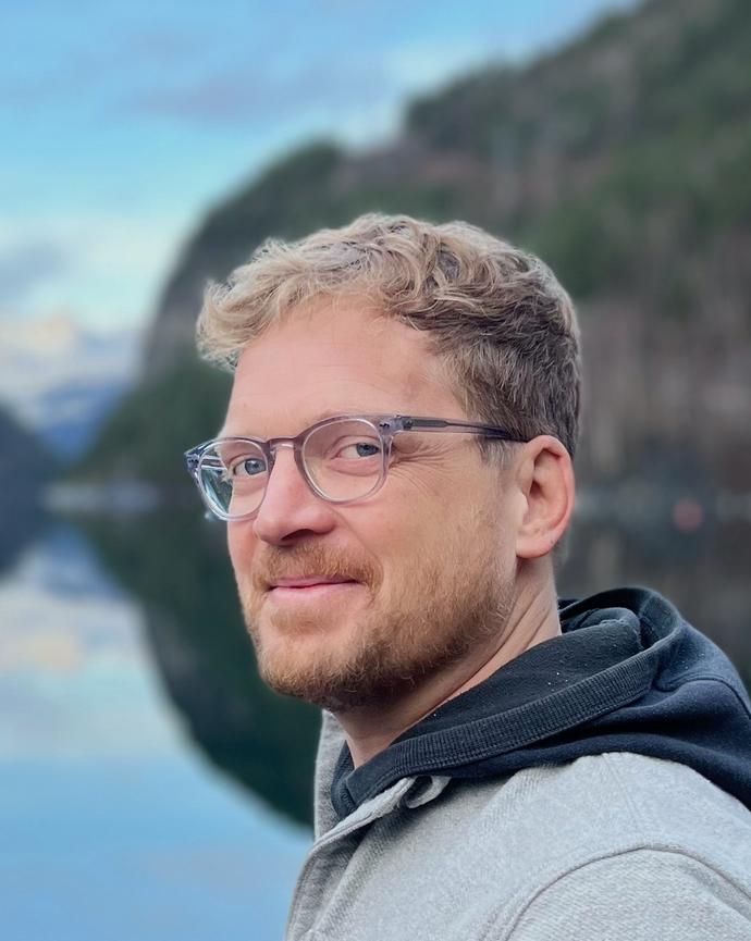 Nate Halverson smiling into the camera, lake and mountains in the background